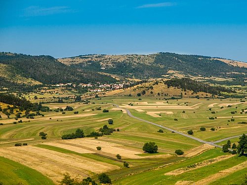 polje s travniki, obdano s hribi, ob vznožju je naselje